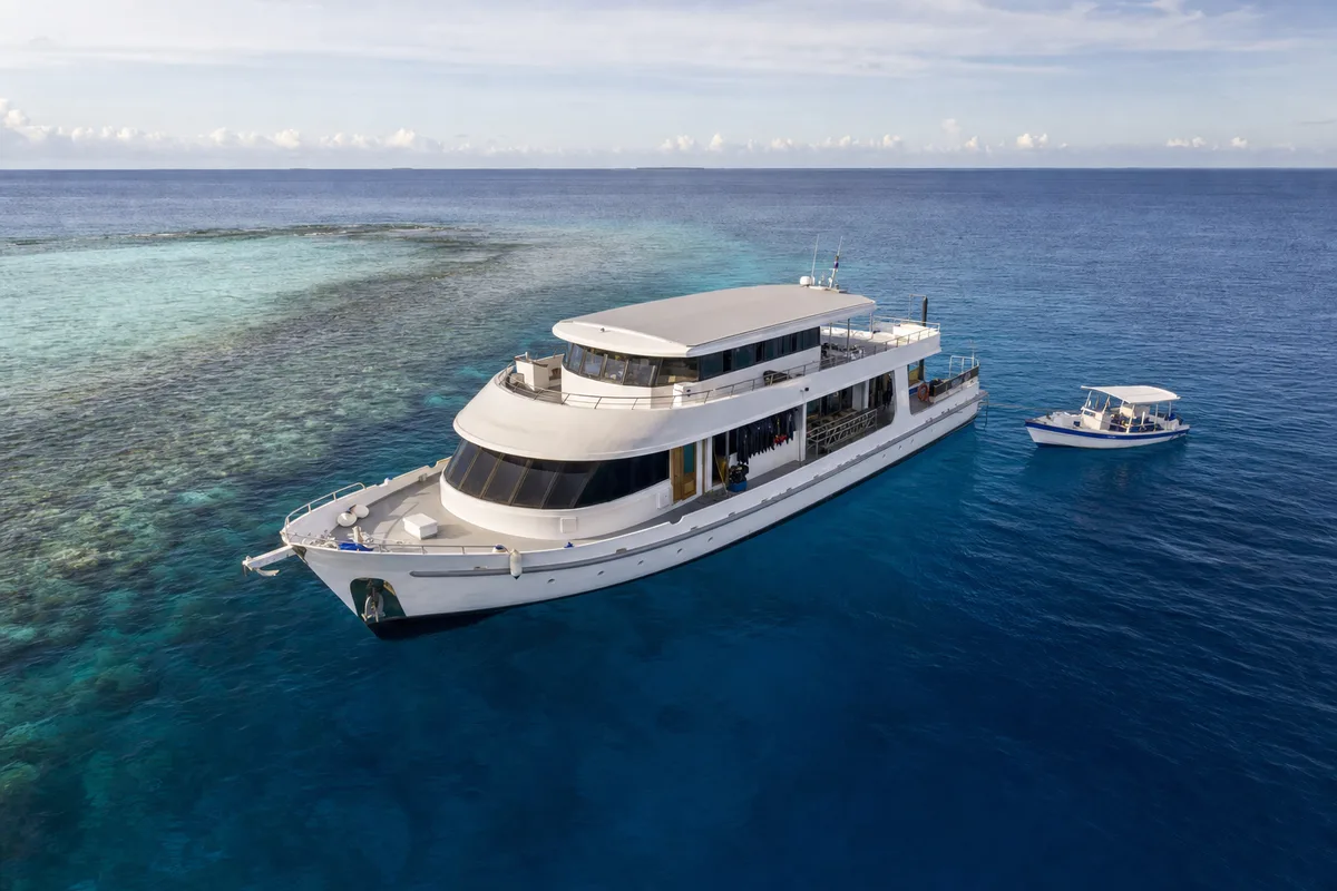 Maldives dive liveaboard cruising beside a coral reef